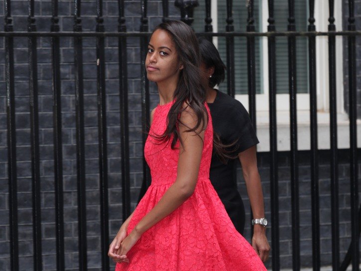 Malia Obama wearing a bright pink dress and walking down the street in London in 2015