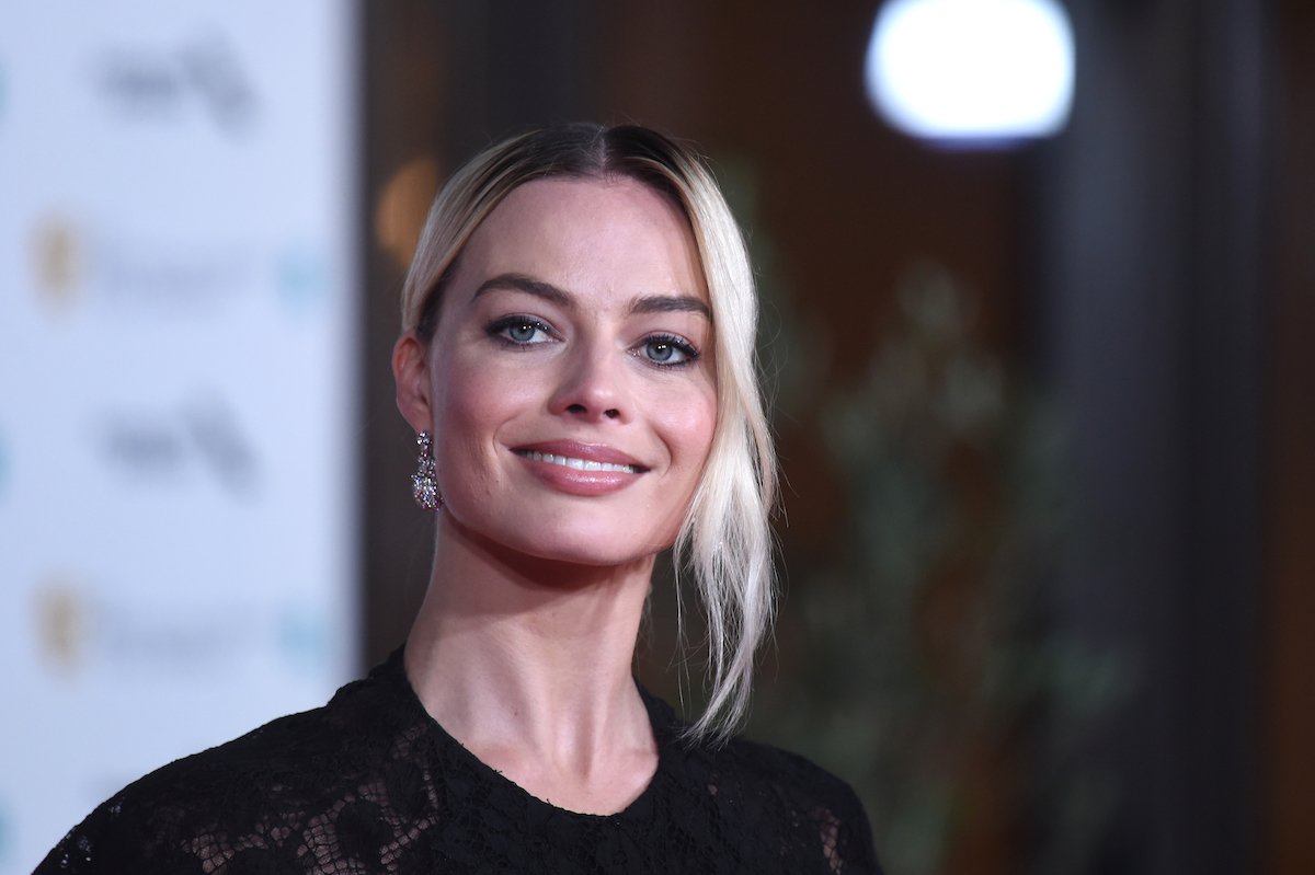 Margot Robbie smiles in a black dress