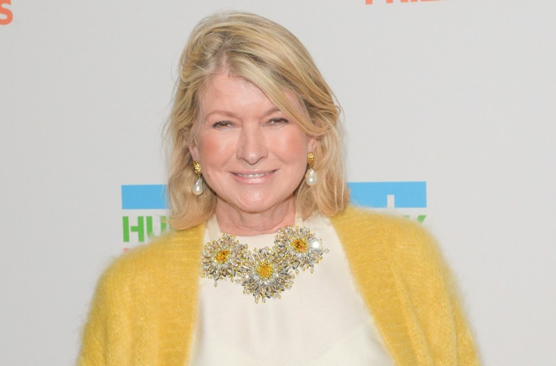 Martha Stewart smiling in a yellow cardigan and white shirt with gold earrings