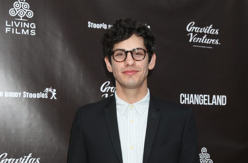 Matt Bennett in a striped button up, blazer, and round glasses at a Hollywood premiere.