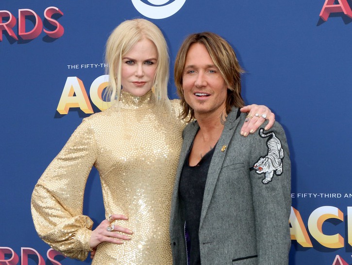 Nicole Kidman in a gold dress with her arm around Keith Urban in a grey suit