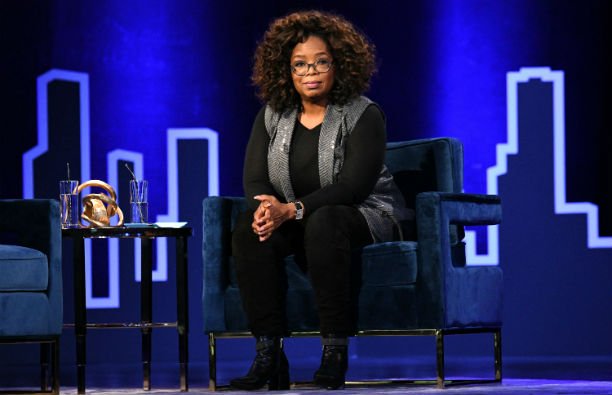 Oprah Winfrey wearing a black top and pants with a gray vest at the Playstation Theater