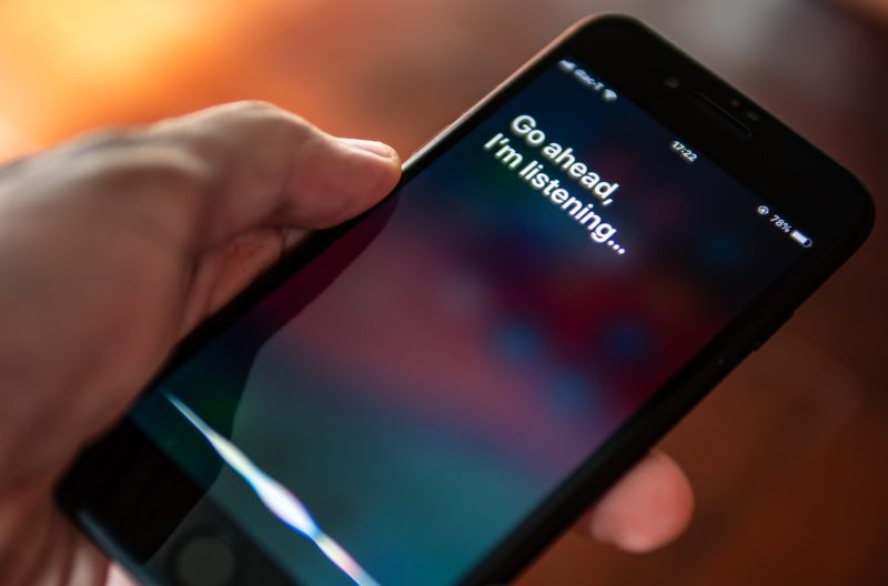 Photo of a hand holding a smartphone using Siri, Apple's voice-activated digital assistant.