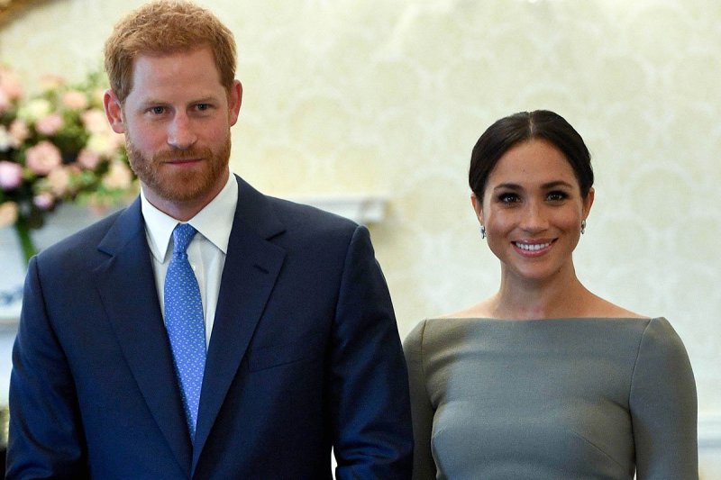 Prince Harry in a blue suit, Meghan Markle in a grey dress