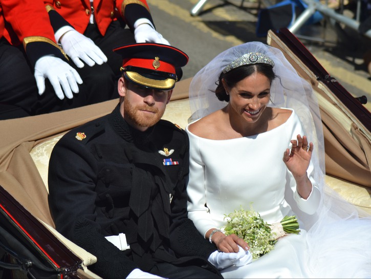 Prince Harry in his military dress sitting with Meghan Markle in a carriage after getting married