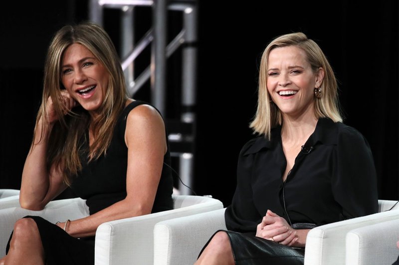 Reese Witherspoon and Jennifer Aniston sitting and laughing together