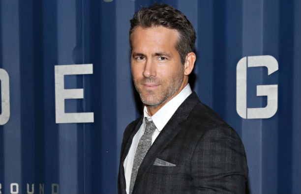 Ryan Reynolds wearing a patterned, dark suit on the red carpet.