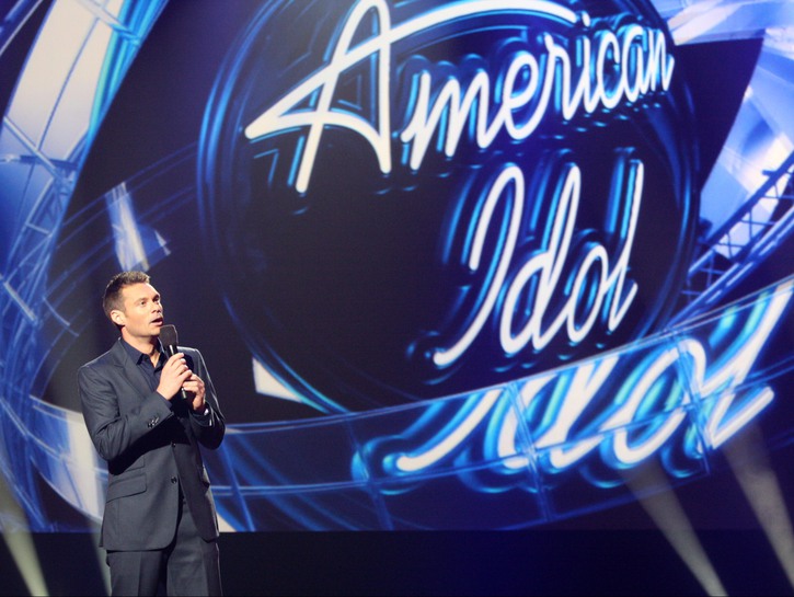 Ryan Seacrest making an announcement on stage at an American Idol event