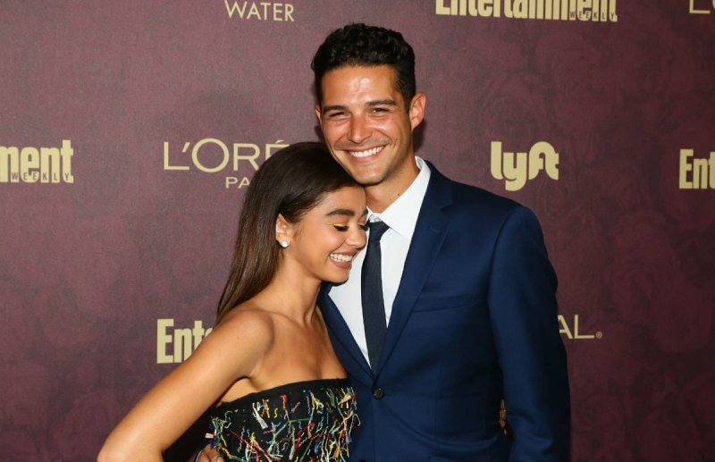 Sarah Hyland in an embroidered black dress standing with Wells Adams, who's wearing a dark blue suit