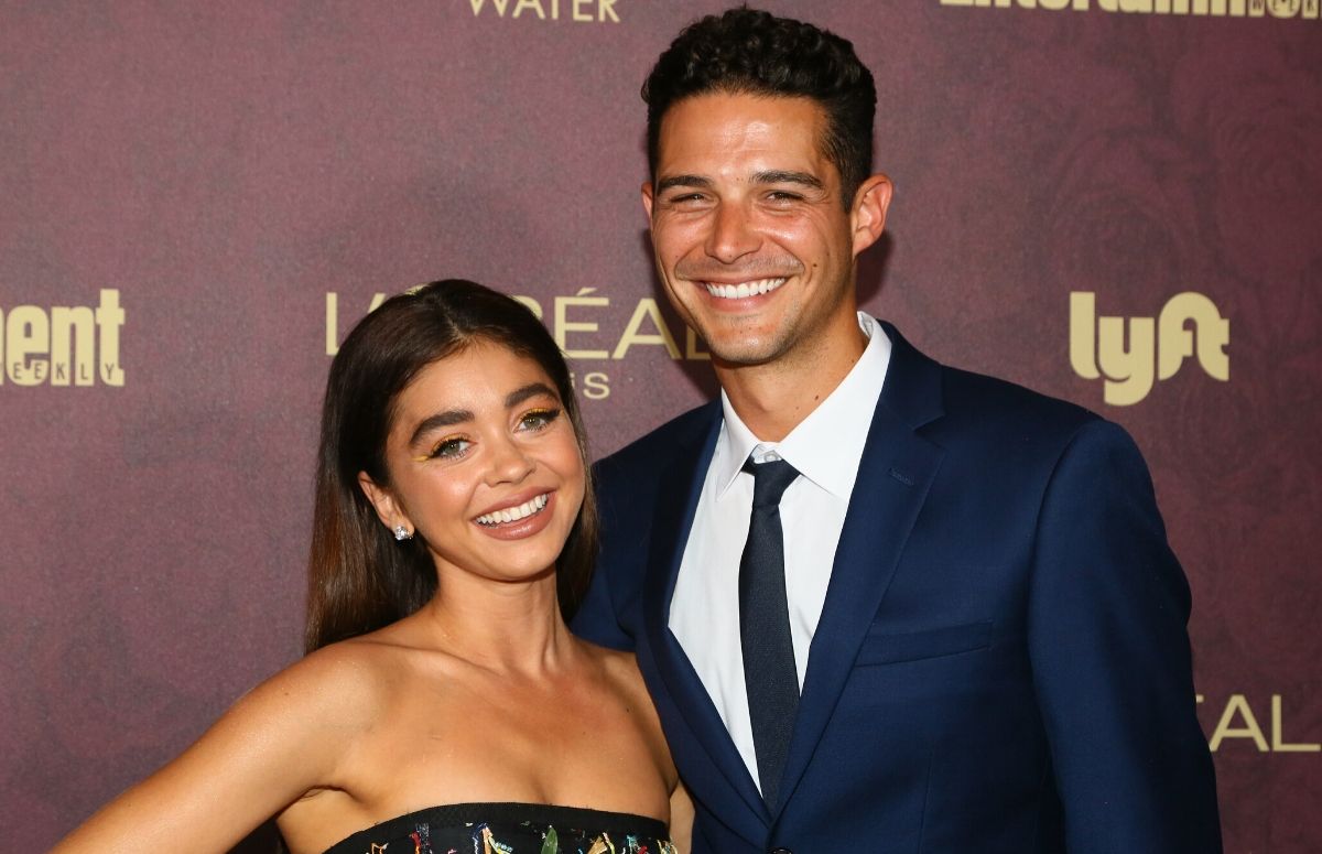 Sarah Hyland wearing a black dress standing with Wells Adams, who's wearing a dark suit, on the red