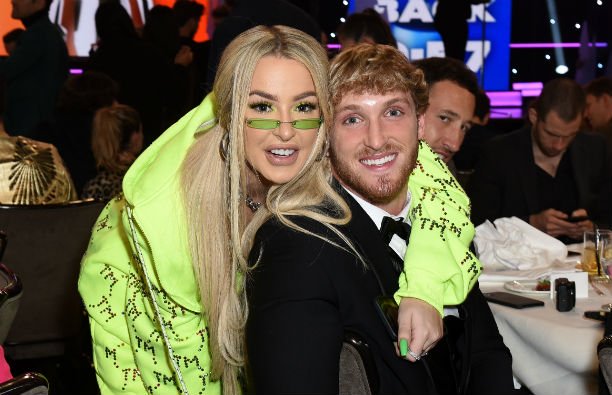 Tana Mongeau wearing a neon green hoodie standing by Logan Paul, who's wearing a black tux, at the S
