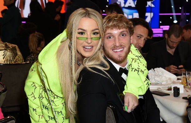 Tana Mongeau wearing a neon green hoodie standing by Logan Paul, who's wearing a black tux, at the S