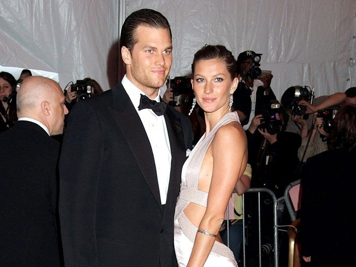 Tom Brady wearing a black tux poses with Gisele Bundchen, in an ivory dress, at the Met Gala