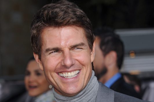 Tom Cruise smiling and wearing gray turtleneck suit in 2013
