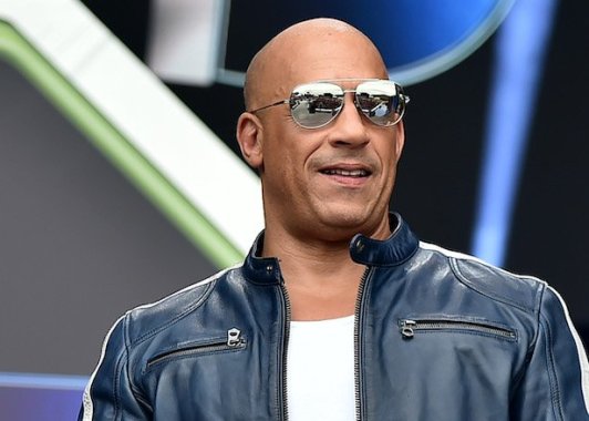 Vin Diesel smiling with reflective sunglasses, black leather jacket, white tank top