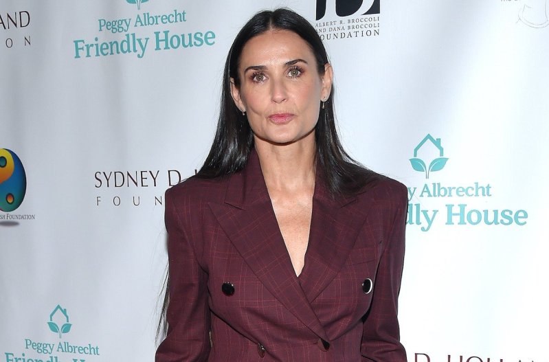 Demi Moore looking at the camera dressed in a maroon suit