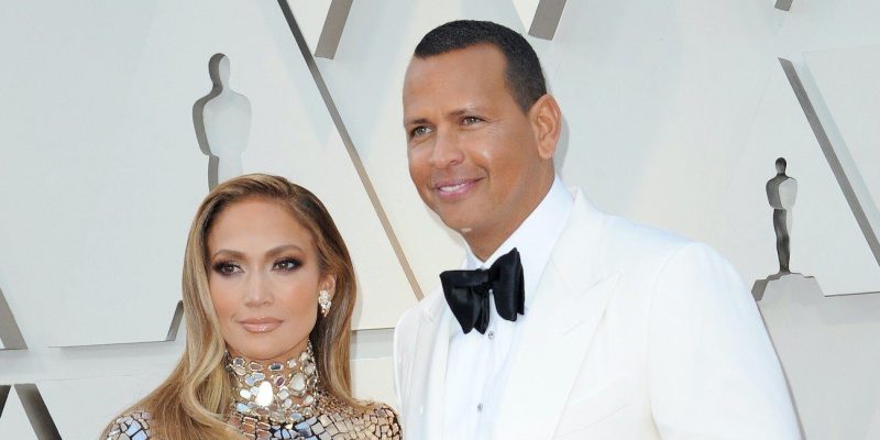 Jennifer Lopez smiling in a silver dress with Alex Rodriguez in a white tux