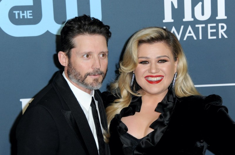 Kelly Clarkson smiling in a black dress with ex-husband Brandon Blackstock in a suit