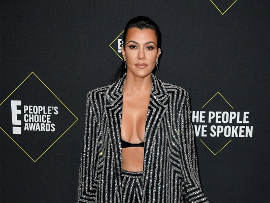 Kourtney Kardashian wearing a jacket, opened to reveal a skimpy bra