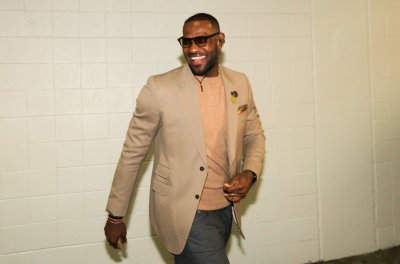 LeBron James wears a tan shirt and suit jacket as he walks into a basketball arena