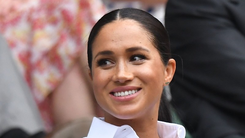 Meghan Markle wears a white shirt and looks to the side