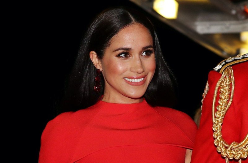Meghan Markle smiling in a red dress