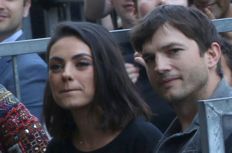 Mila Kunis and Ashton Kutcher sit in the crowd at a Hollywood Walk Of Fame Ceremony
