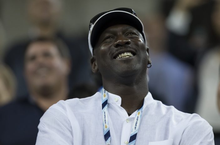 Michael Jordan wearing a white button down shirt, smiling and looking up towards the sky.