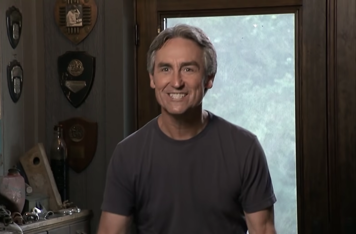 Mike Wolfe smiling and wearing a grey t-shirt during a confessional on 'American Pickers'