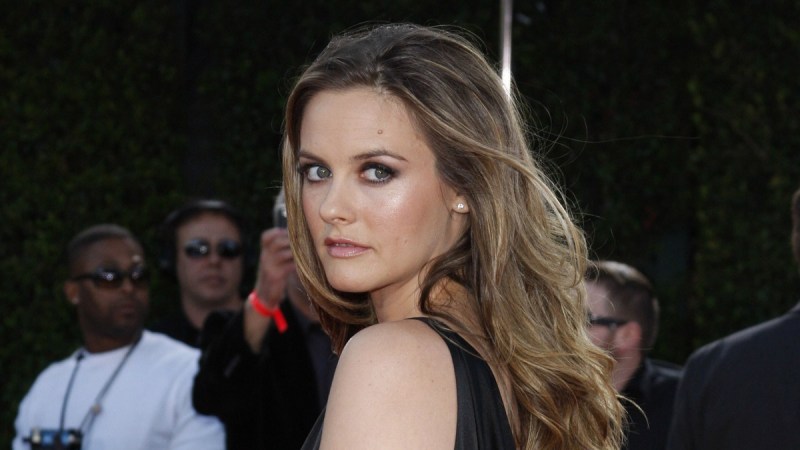 Alicia Silverstone wears a black dress and looks over her shoulder