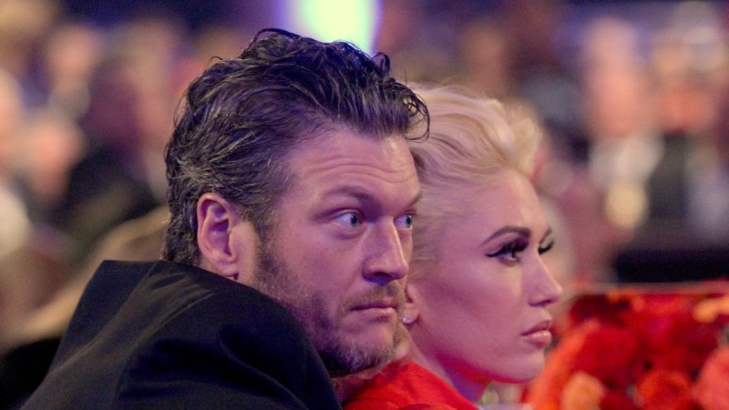 Blake Shelton, in a dark blazer, cuddles up with Gwen Stefani, in a red dress