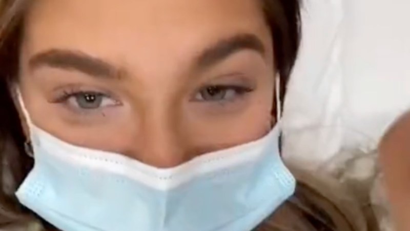 Claudia Conway wears a hospital gown and face mask in the hospital