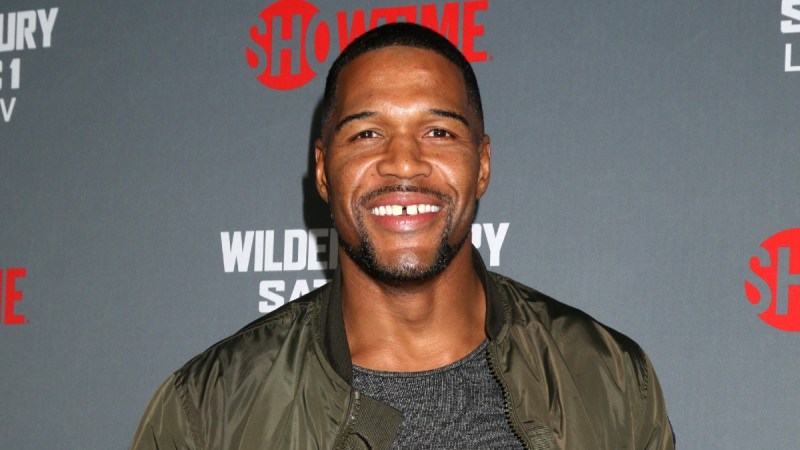 Michael Strahan wears a green jacket over a dark t shirt on the red carpet