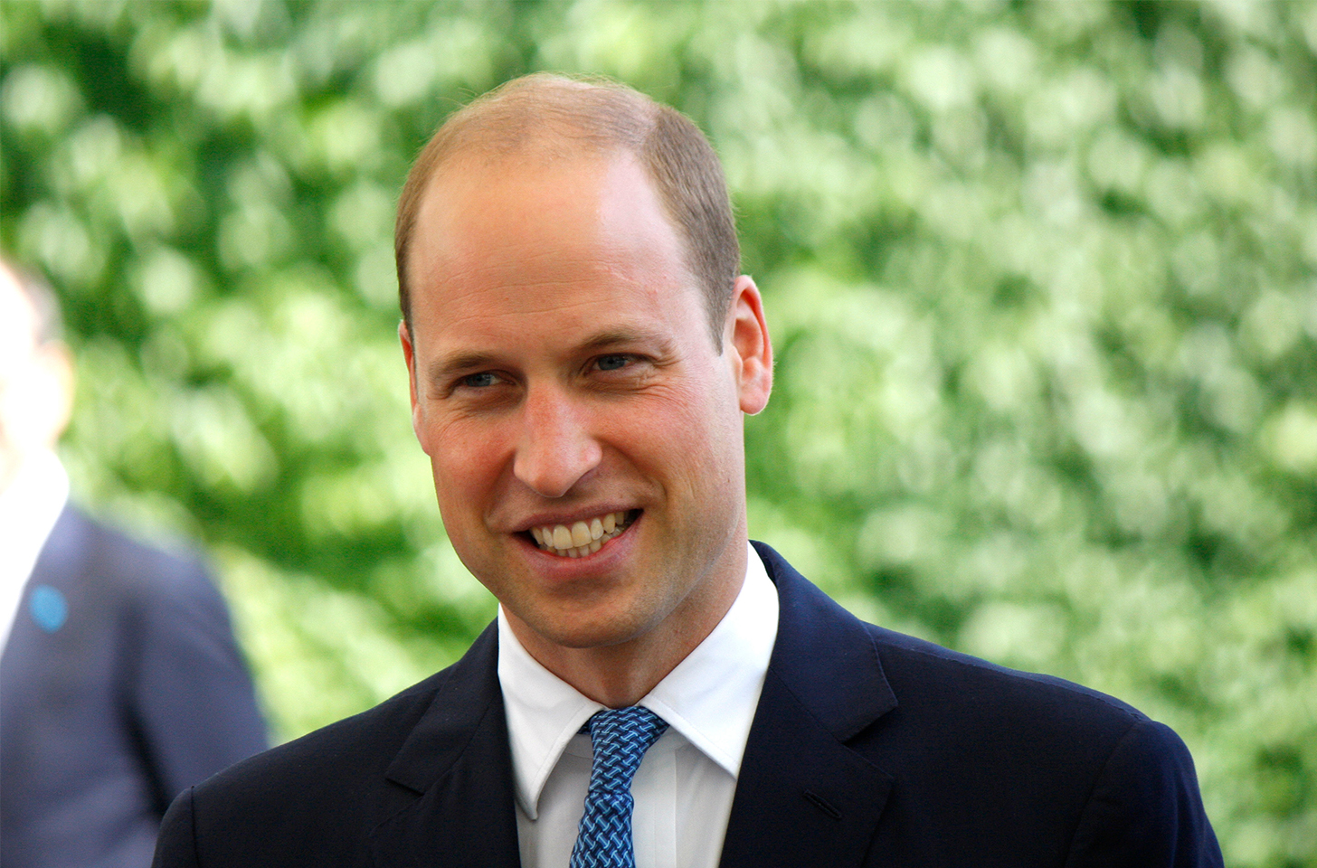 Close up of Prince William, smiling and bald.