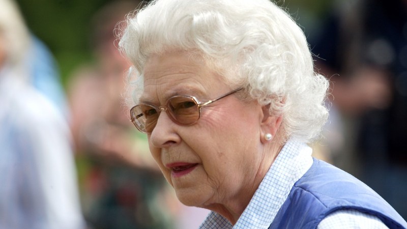 Queen Elizabeth wears a blue sweater vest as she greets a crowd