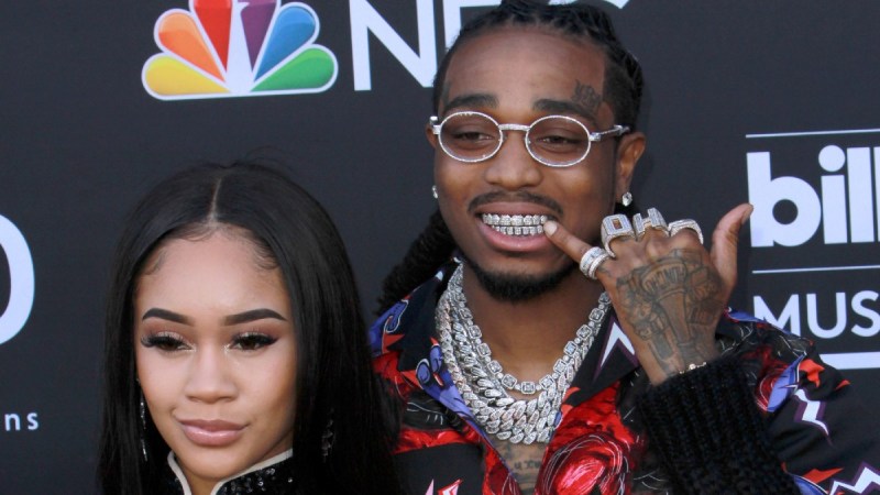 Saweetie stands with Quavo against a black background