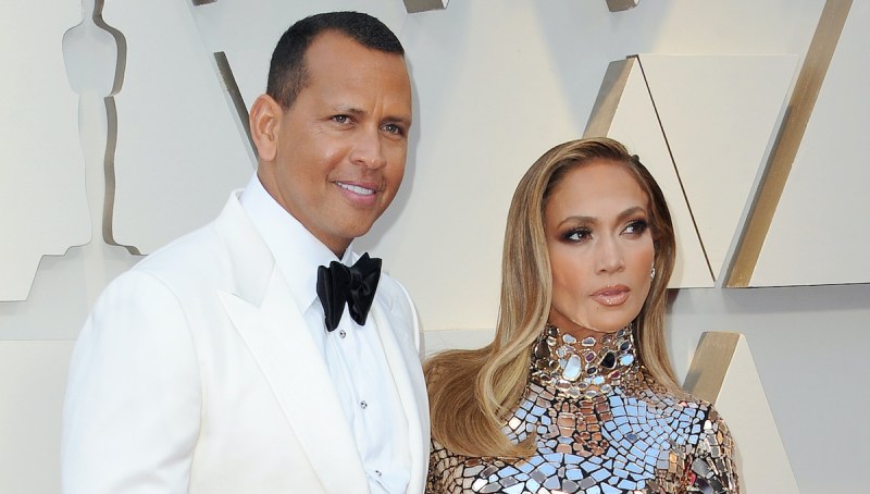Alex Rodriguez in a white tuxedo with Jennifer Lopez in a silver dress