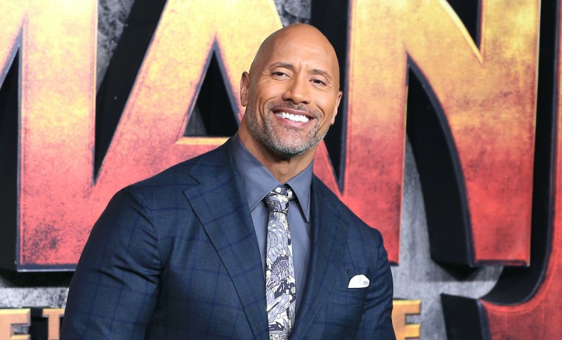 Dwayne Johnson smiles in a suit