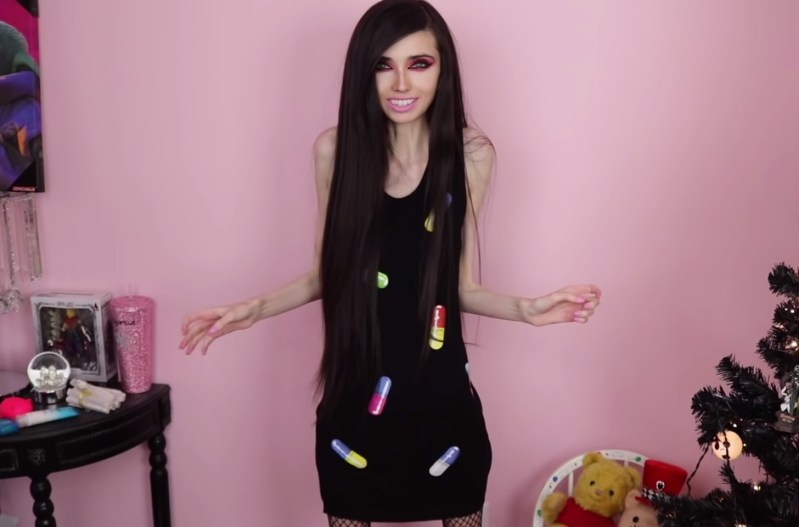 Eugenia Cooney wearing a black dress with colorful pills printed on the front.