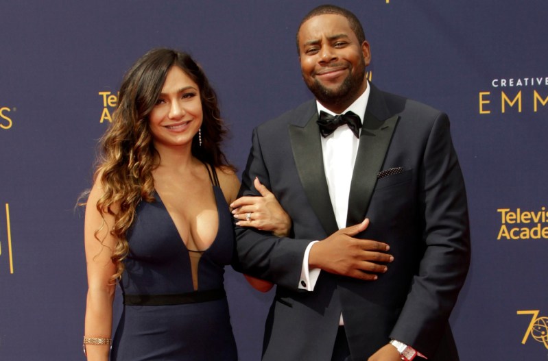 Kenan Thompson in a black suit, locking arms with his wife, Christina Evangeline, who is wearing a navy blue dress.