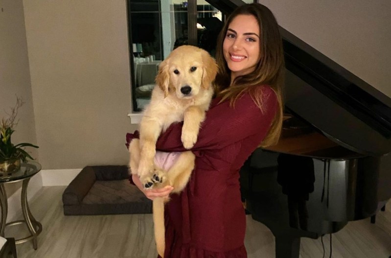 Nickmercs wife wearing a red dress and holding a yellow dog.