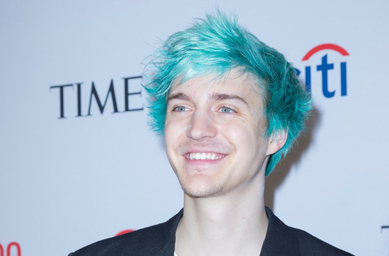 Ninja smiling with blue hair and a black jacket.