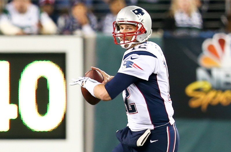 Tom Brady playing a football game for the Patriots, getting ready to throw a ball.