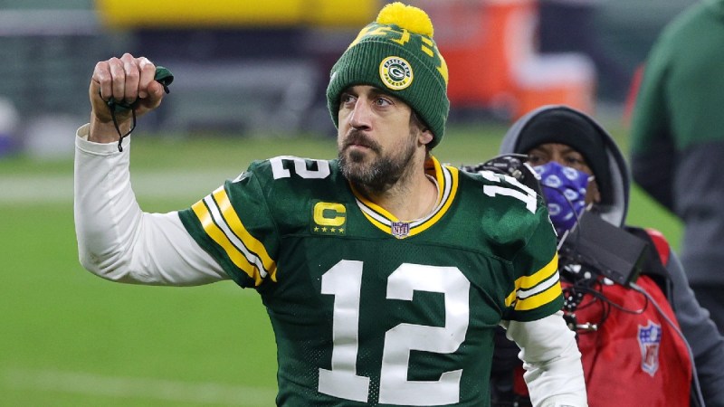 Aaron Rodgers wears his Green Bay Packers jersey and holds up a fist as he walks across the field