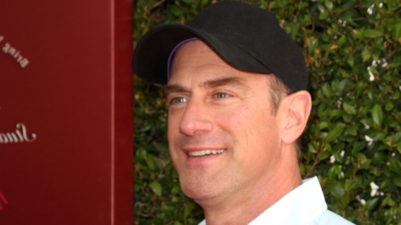Christopher Meloni wears a white shirt and black ball cap on the red carpet