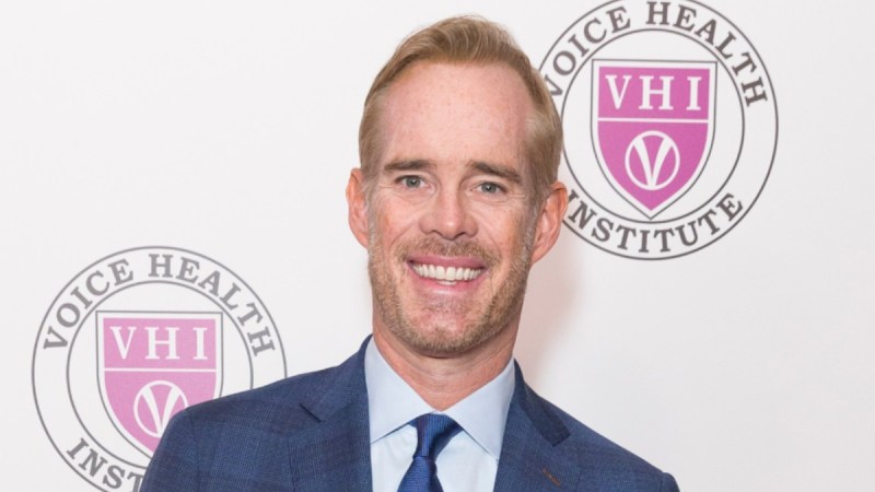 Joe Buck wears a blue suit as he stands against a white background