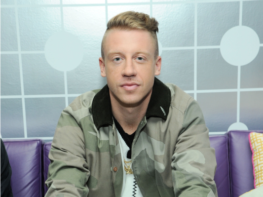 Macklemore sitting in green jacket with black collar