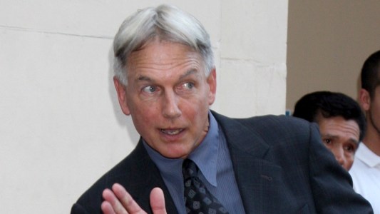 Mark Harmon wears a dark suit and holds up a hand during his Hollywood Walk Of Fame ceremony