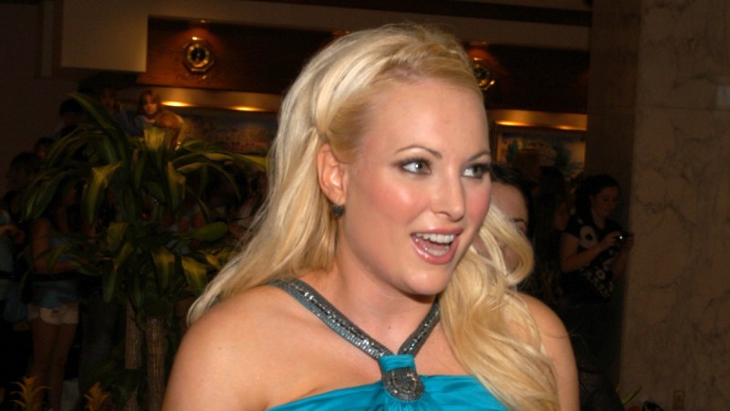 Meghan McCain wears a teal dress with her hair loose as she smiles at someone off camera