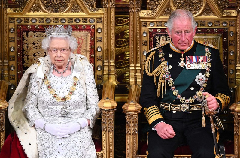 Queen Elizabeth sitting next to Prince Charles on thrones in the House Of Lords.